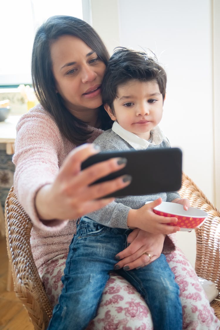 Woman Holding Her Smartphone Taking  Photo With A Boy 