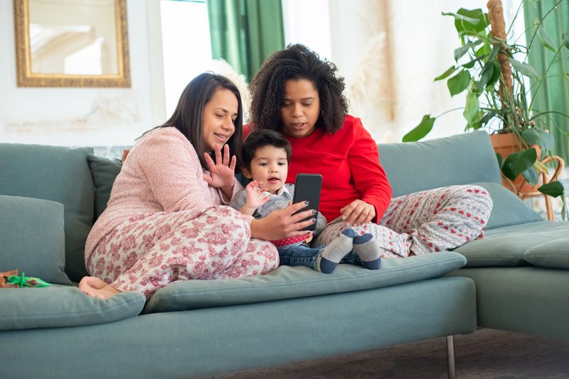 A family bonding on the sofa while looking at a mobile phone screen together at home