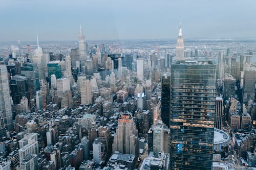 Drone view of modern high rise buildings and residential houses located on street of New York City against cloudless sky