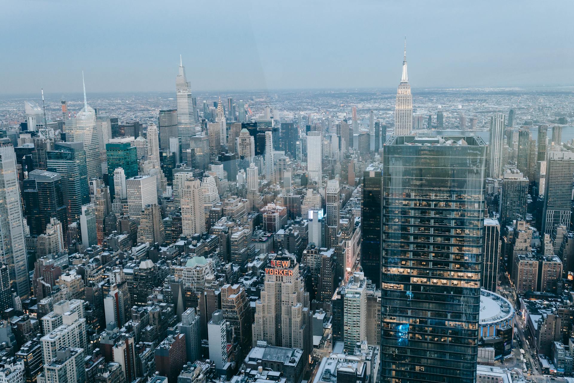 Drone view of modern high rise buildings and residential houses located on street of New York City against cloudless sky