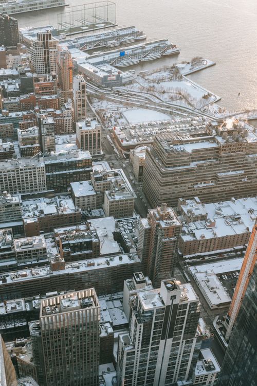 Free Drone view of tall modern residential houses located on snowy waterfront near calm sea in city on cold winter day Stock Photo