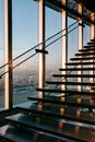 Stairway with metal railing located in contemporary business center with bright sunlight near glass wall overlooking modern city with buildings
