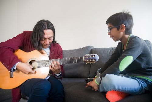A Guitarist Teaching a Boy How to Play the Guitar