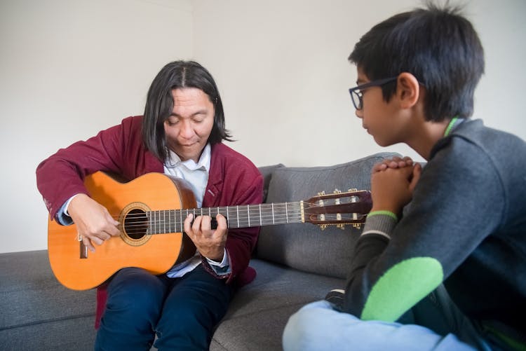 A Music Teacher Showing A Boy How To Play A Guitar