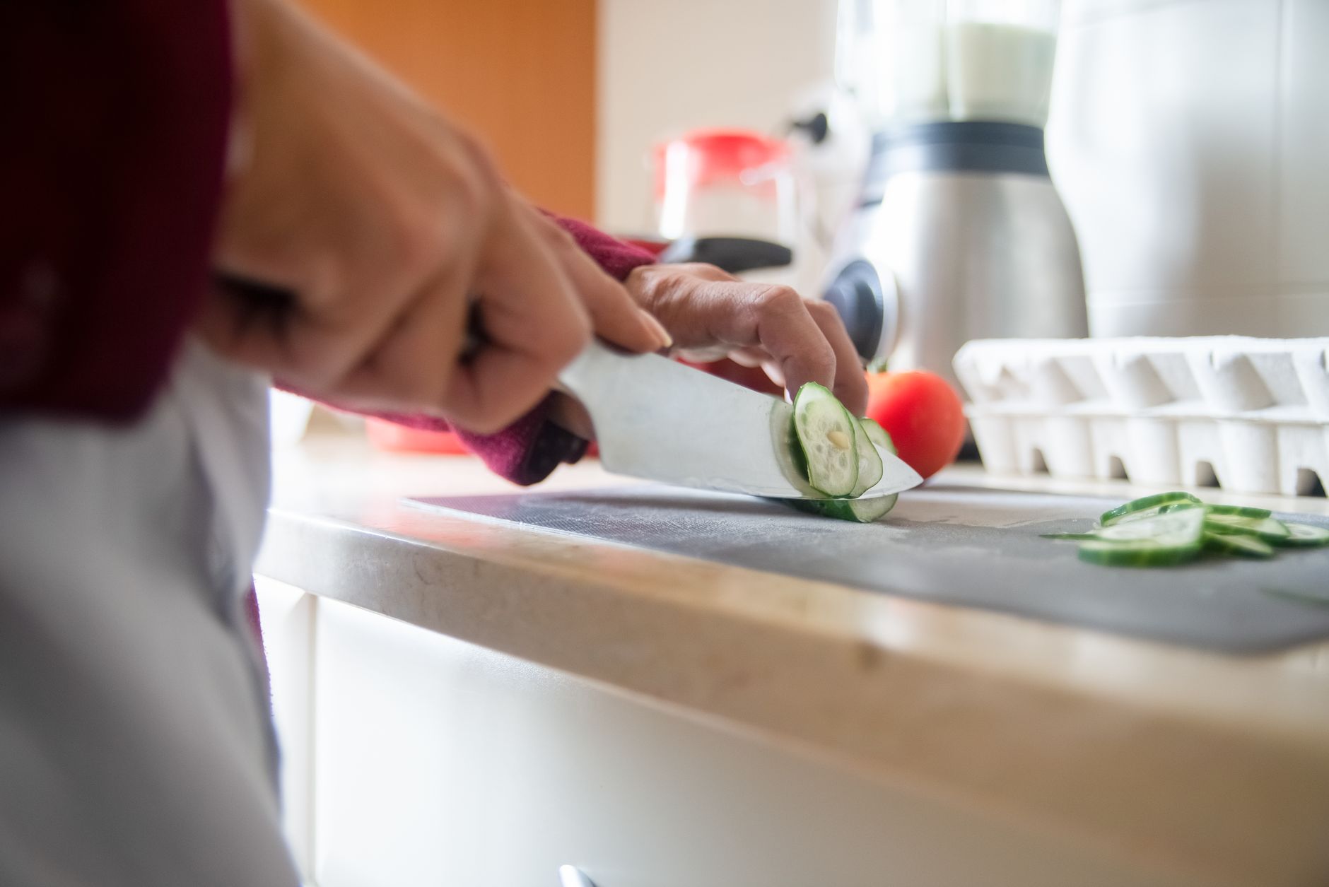 Close-up of a person slicing cucumbers on a kitchen counter for a healthy meal prep.