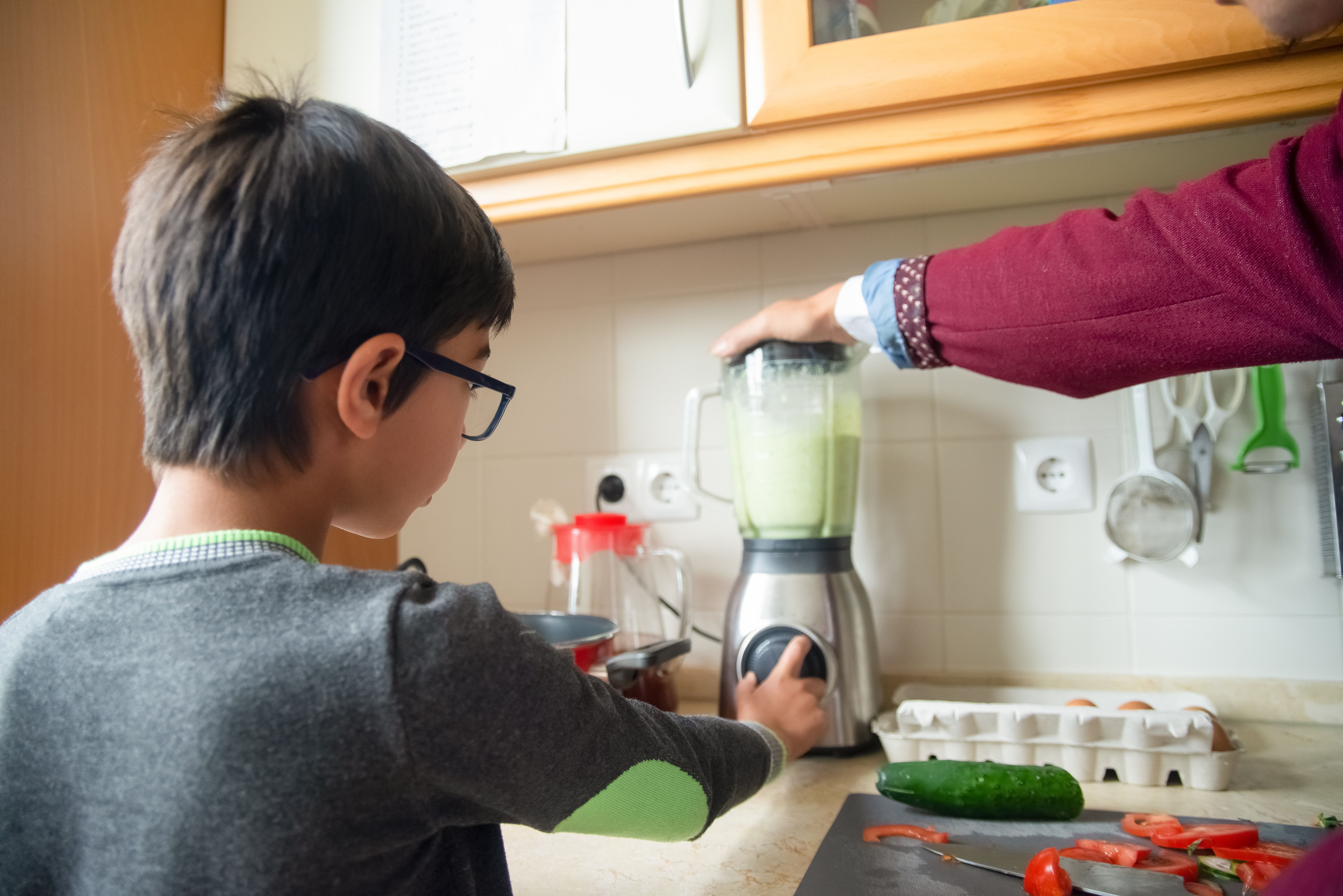 A father and son team up to make a healthy smoothie in a modern kitchen.