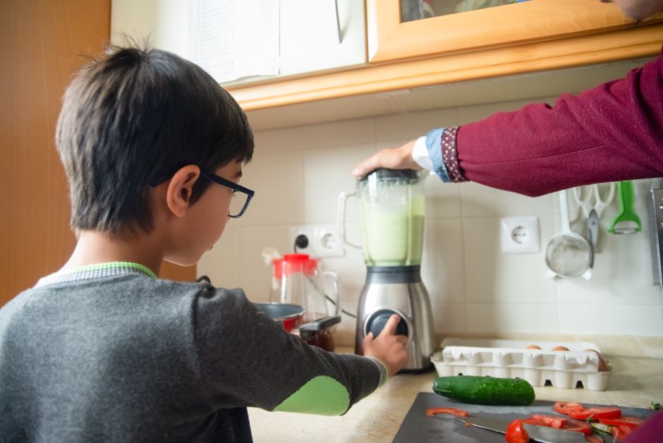 A father and son team up to make a healthy smoothie in a modern kitchen.