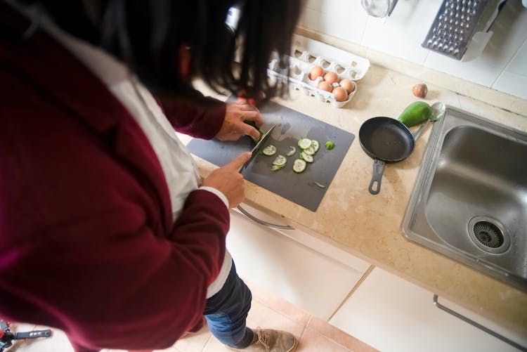 A Person Slicing Cucumber With A Knife