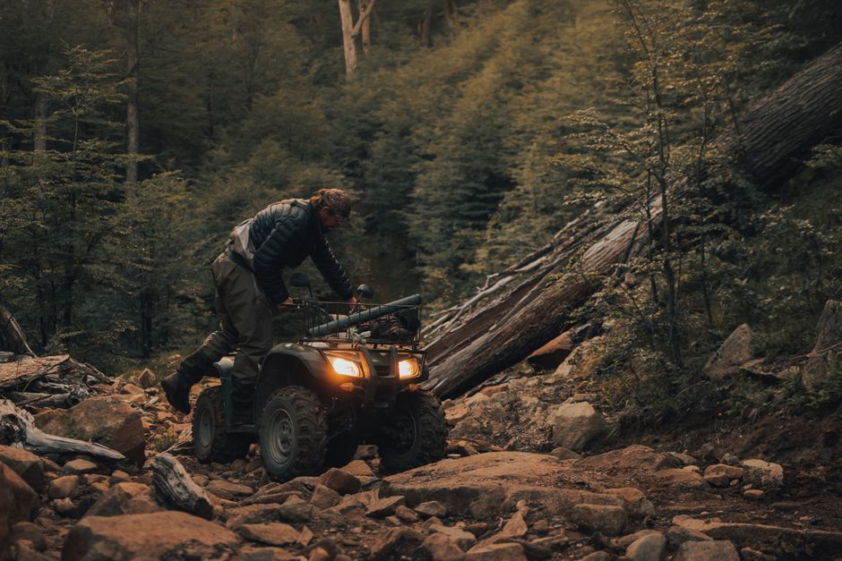 Man riding an ATV on a rugged forest trail, showcasing adventurous outdoor exploration.