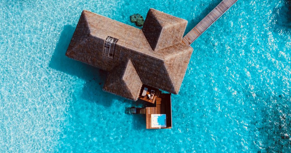 A stunning aerial view of a luxurious overwater villa in the Maldives surrounded by crystal clear blue waters.