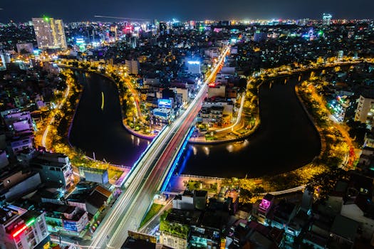Breathtaking night view of Ho Chi Minh City with vibrant city lights along a river and bustling streets.