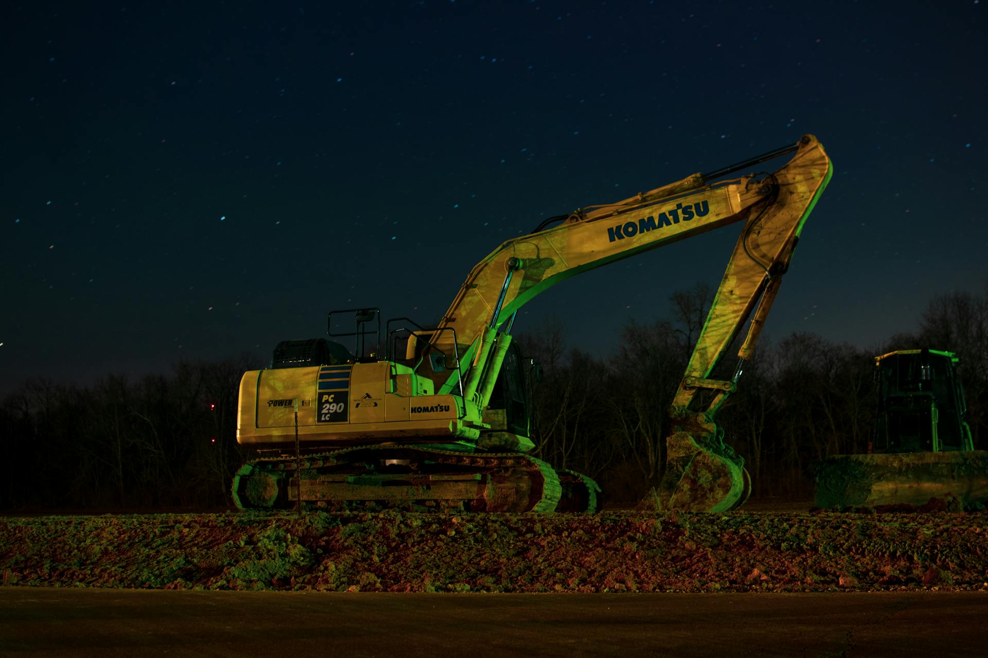 A Komatsu excavator at night, highlighting its silhouette against a starry sky.