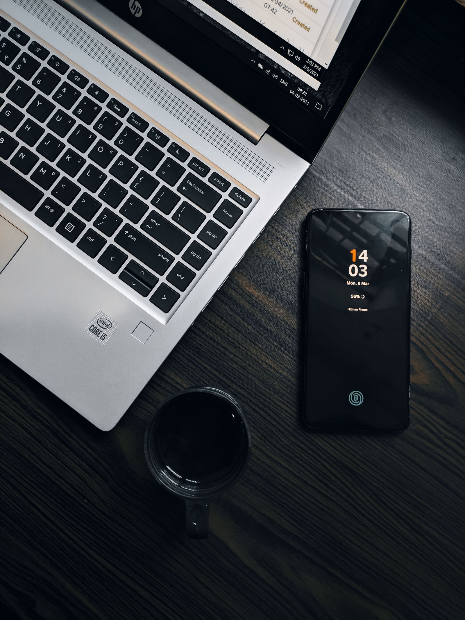 A smartphone beside a laptop on a dark desk, representing cleaning a photo on any device before it is shared