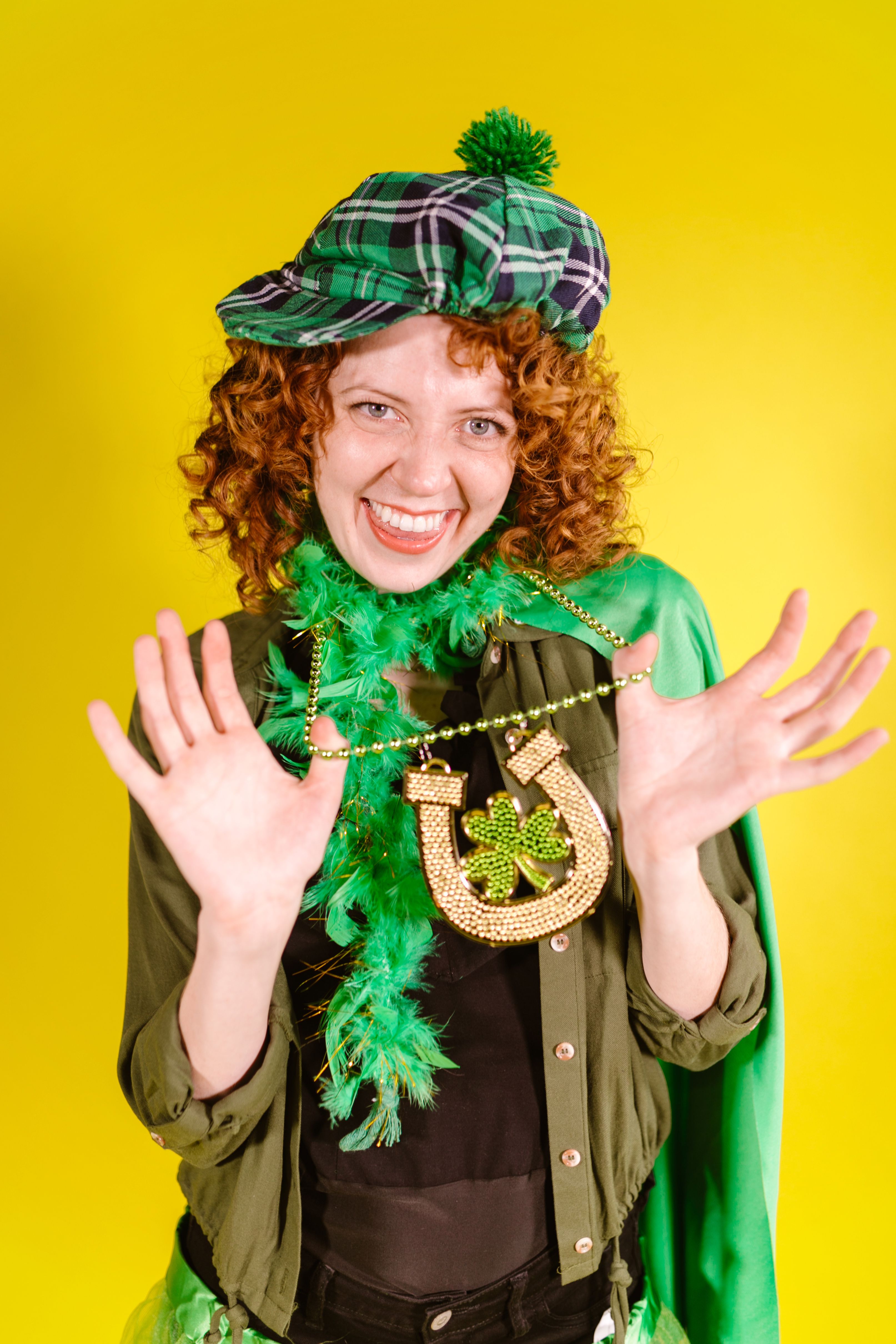 Cheerful woman in festive green attire celebrating Saint Patrick's Day with a golden horseshoe necklace.