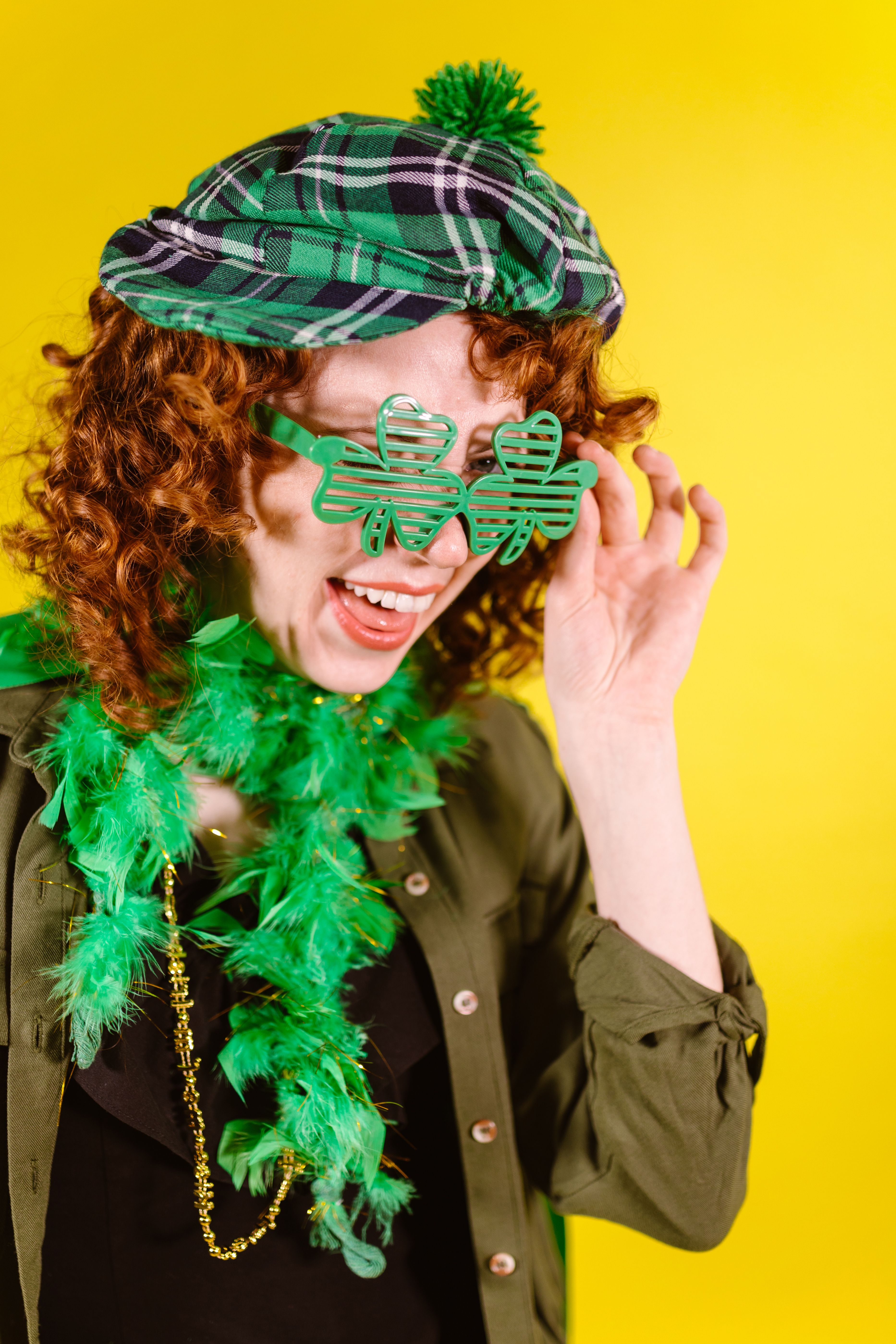 Caucasian woman in green attire celebrating St. Patrick's Day with joy.