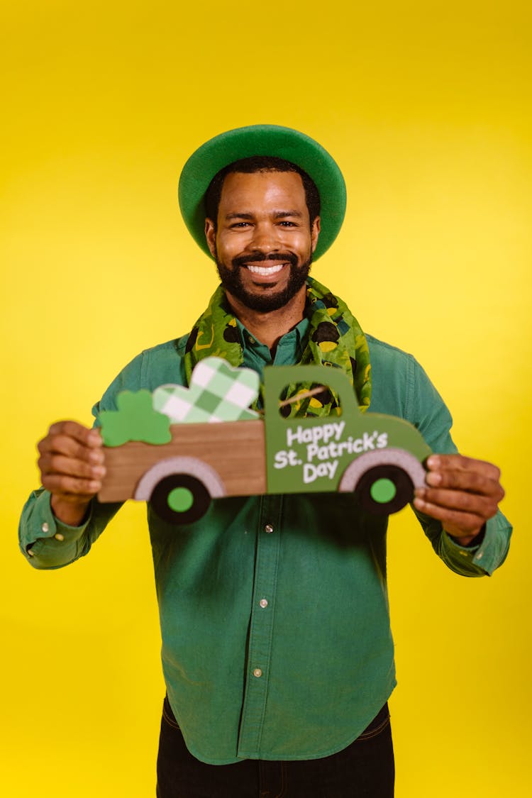 Smiling Man Wearing A Green Hat Holding A Prop 