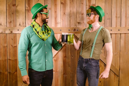 Smiling Men holding Clear Glass Mug with Green Beer 
