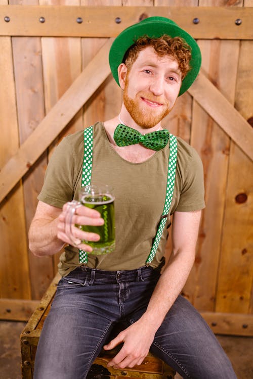 Man wearing a Green Hat holding Glass Mug with Green Beer 