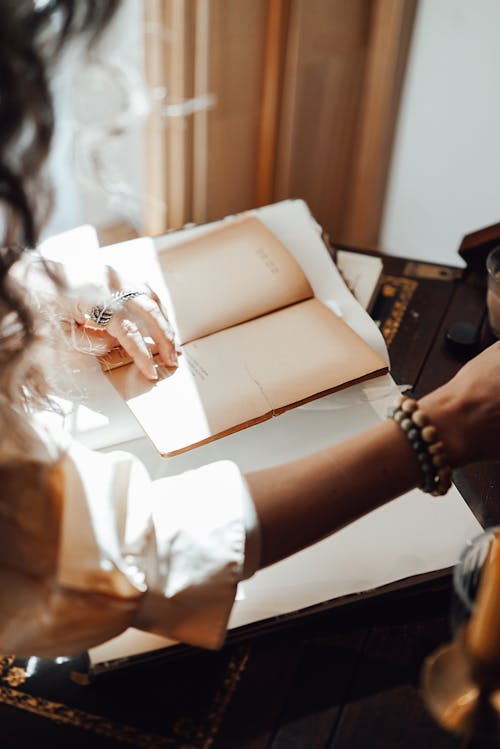 Free Crop writer at old table with notebooks in sun ray Stock Photo