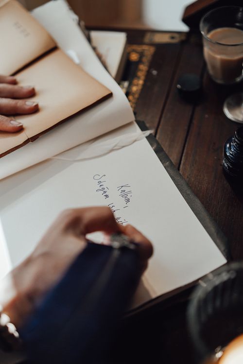Free From above of crop unrecognizable female writer taking notes in notepad with feather at vintage table in house Stock Photo
