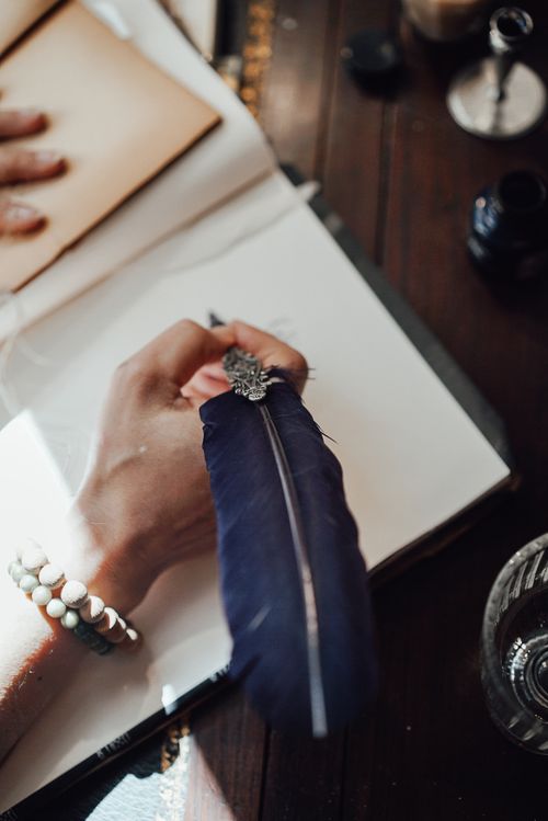 Free High angle of crop anonymous female author with feather and blank notebook at desk in sun ray Stock Photo