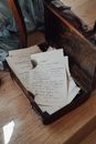 From above of opened aged suitcase with abundance of ink letters with burnt edges placed on wooden floor in room