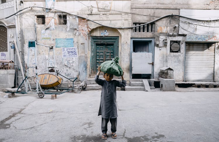 Photograph Of A Kid Carrying A Sack