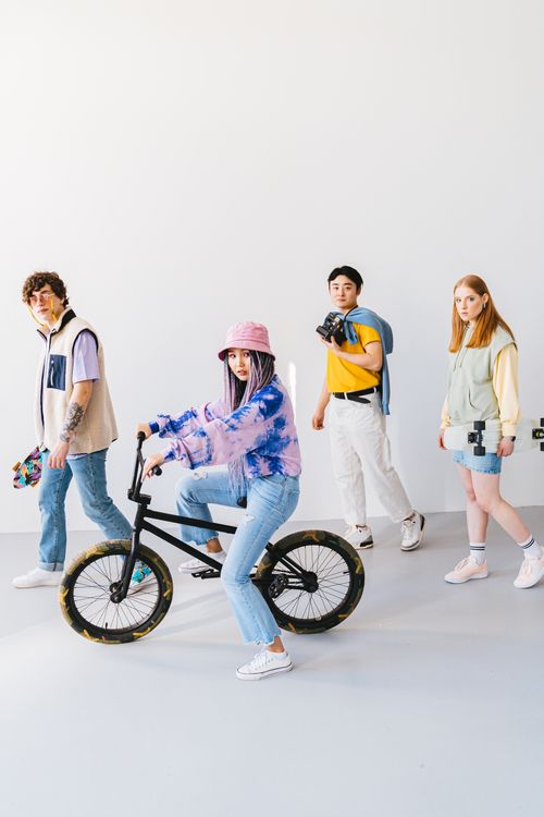 Free A stylish group of friends posing with a BMX and skateboards in a bright studio setting. Stock Photo
