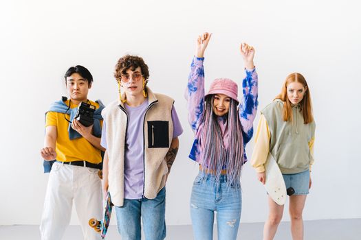 A stylish and diverse group of young adults posing with skateboards in a studio setting.