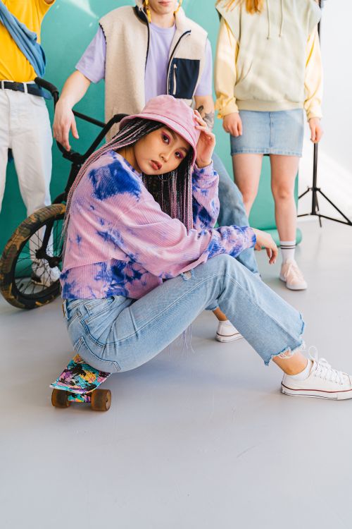 Free Group of trendy teens posing with a skateboard, embracing casual street style indoors. Stock Photo