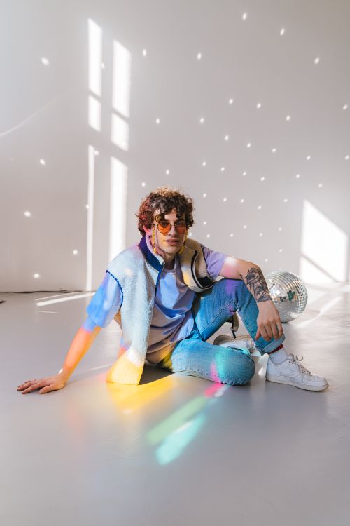 Free Fashion-forward individual sits amidst disco vibes with a colorful twist. Stock Photo