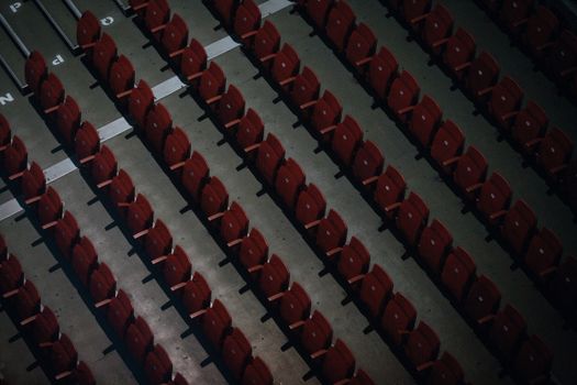 Overhead shot of aligned empty red stadium seats in rows.