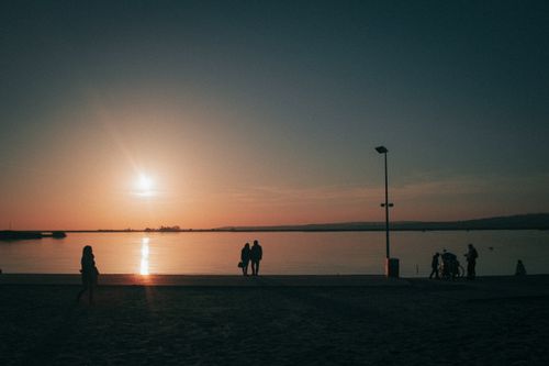 Free Silhouetted figures by a river at sunset create a peaceful vignette in Hungary. Stock Photo
