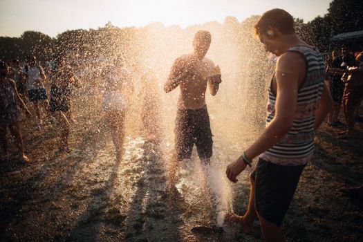 Group of people playing in water at sunrise outdoors in Budapest, capturing joyful summer moments.