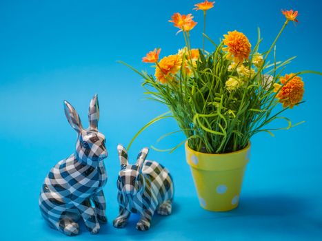 Vibrant Easter themed decor featuring checkered bunny figurines and yellow flowers in a polka dot pot.