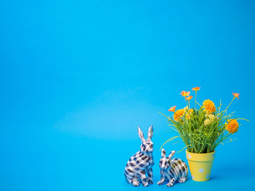 Colorful spring setup featuring ceramic bunnies and flowers against a blue background.