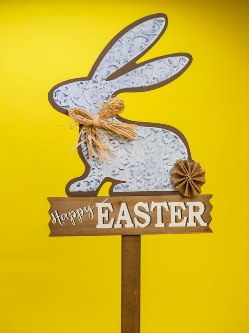 Free Decorative Easter bunny sign with 'Happy Easter' text and rustic embellishments on a bright yellow backdrop. Stock Photo