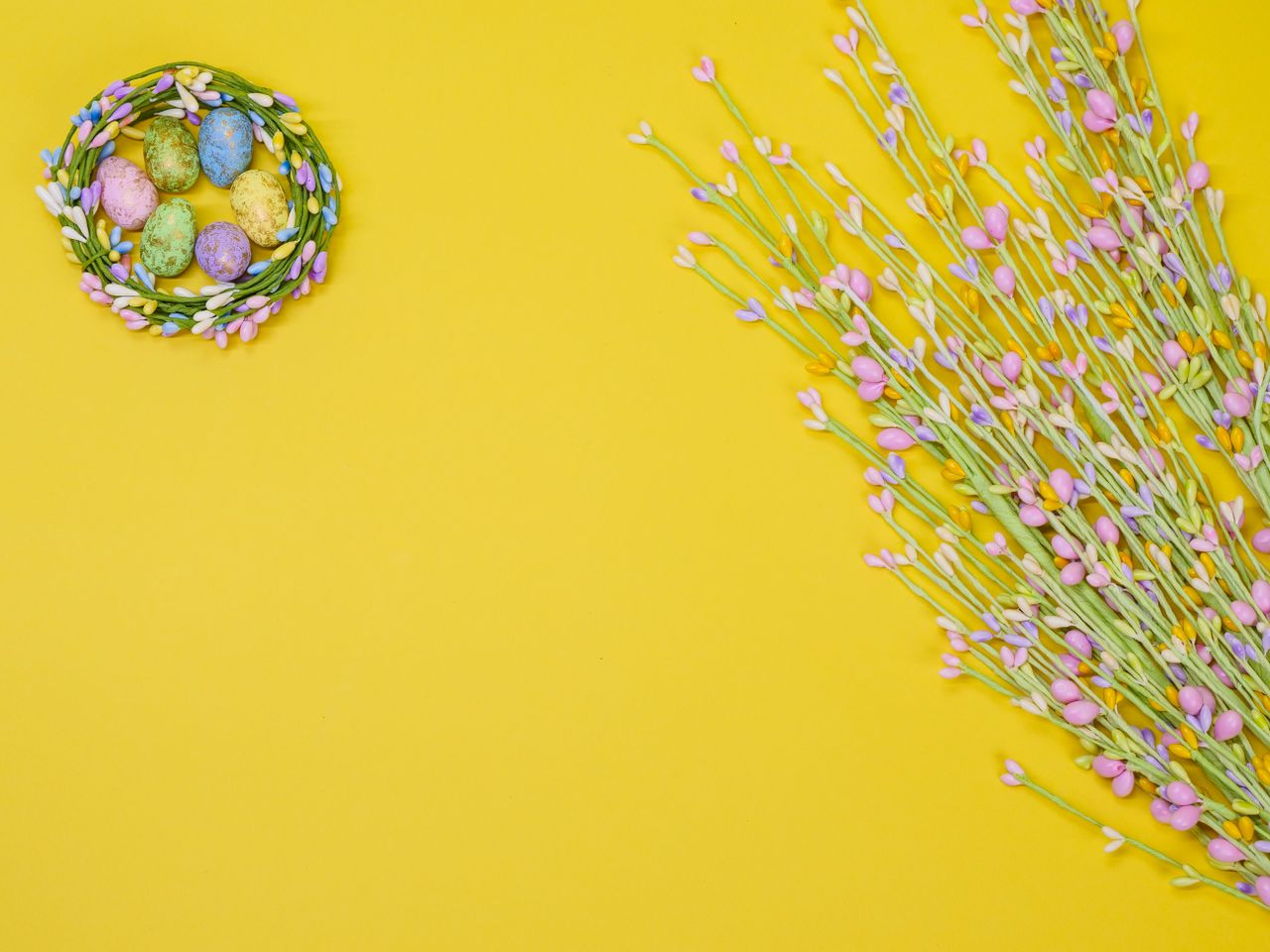 decorative easter eggs in a floral nest against a vibrant yellow backg