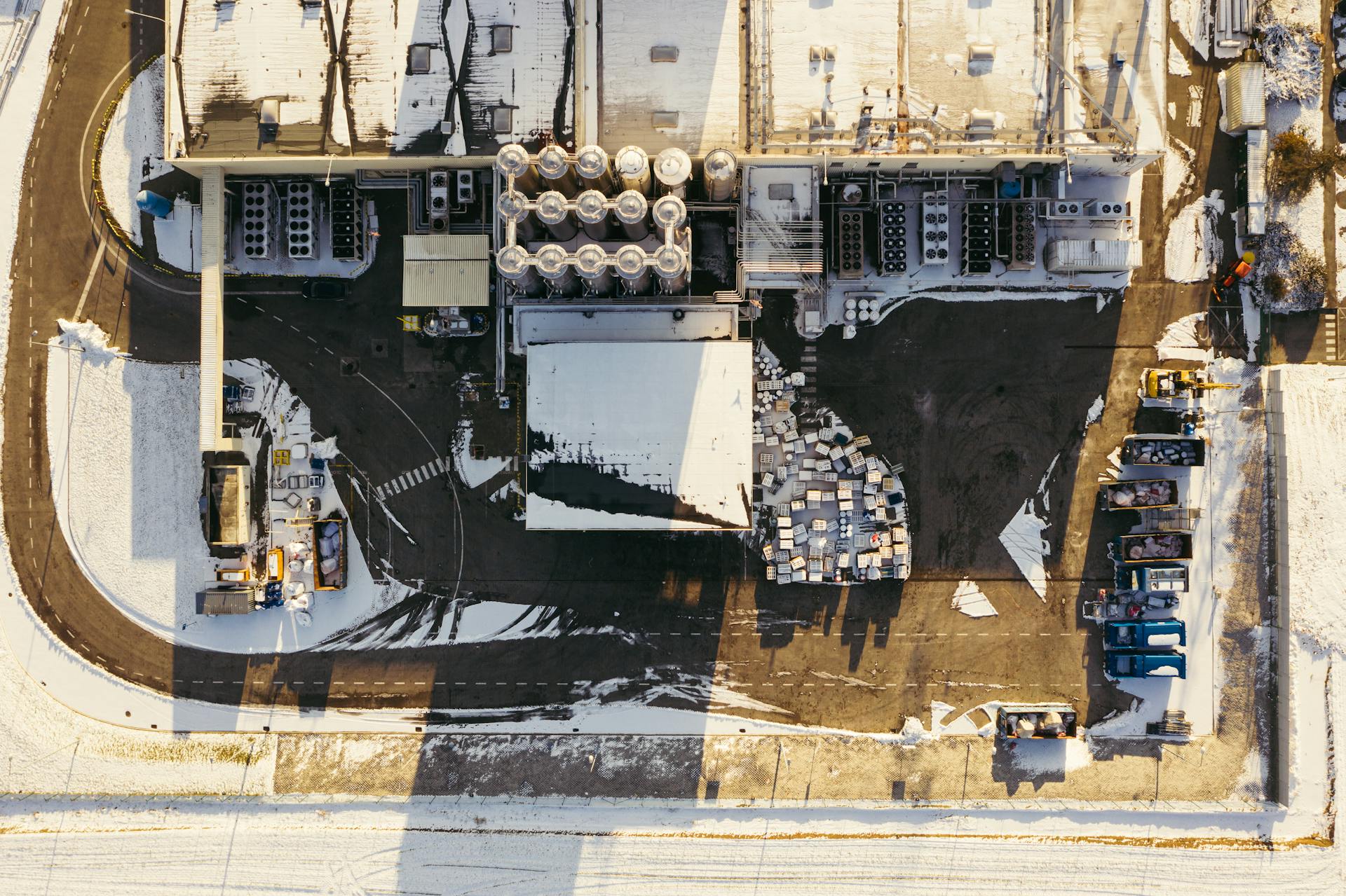 Aerial shot of an industrial plant covered in winter snow in Poland, showcasing infrastructure and storage areas.