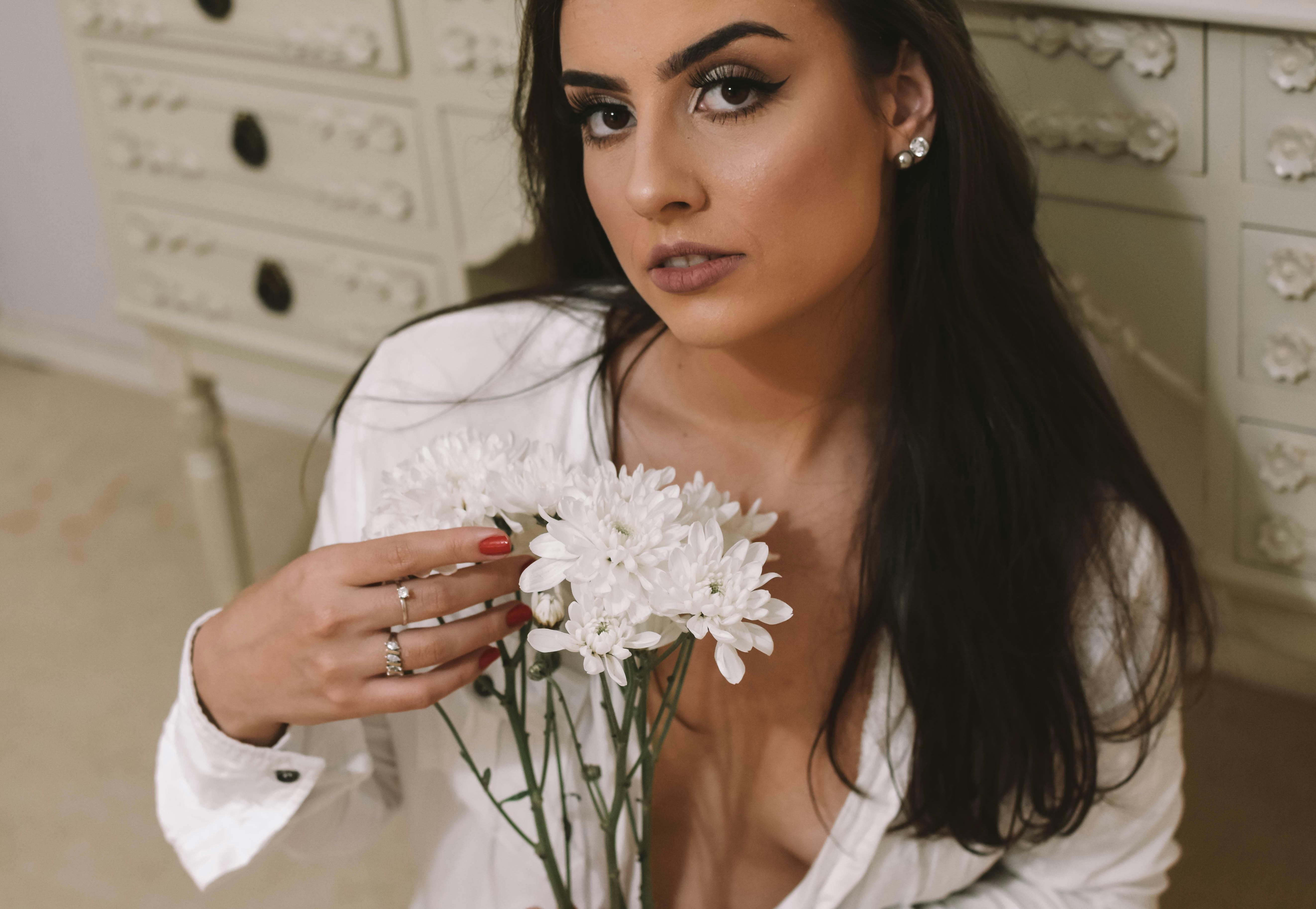 A young woman holding white chrysanthemums, exuding charm and elegance.