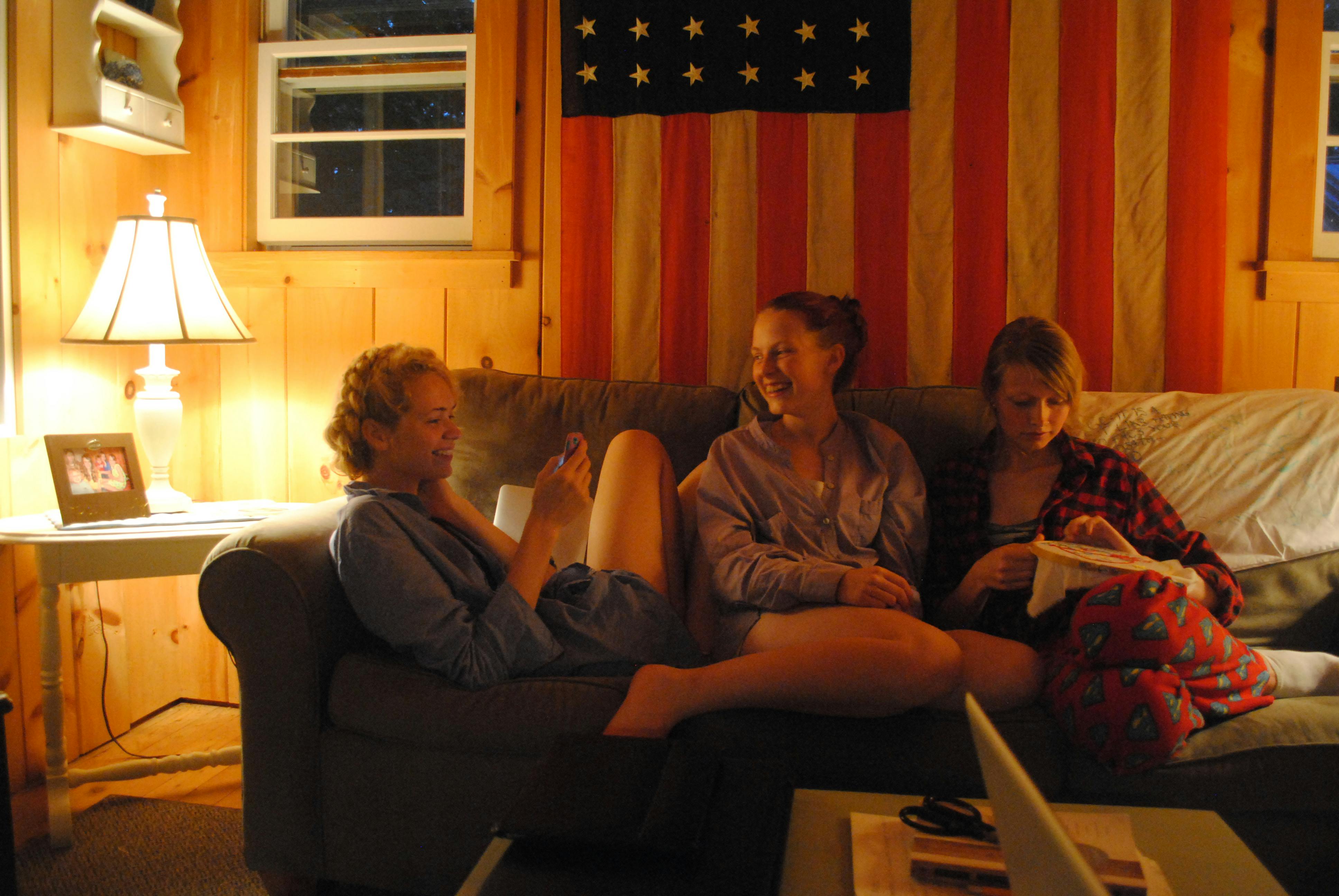 happy young ladies smiling while talking on couch in evening