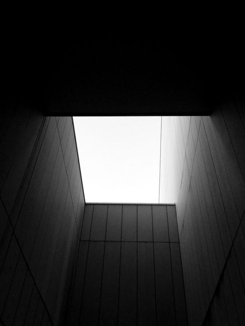 From below of black and white walls of modern geometric buildings on sunny day