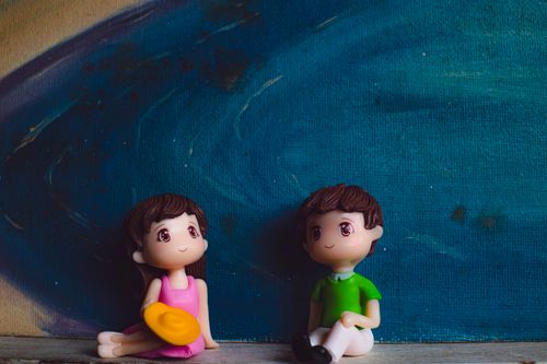 Free Small plastic figures of man with girlfriend sitting against canvas with artwork of blue ocean Stock Photo