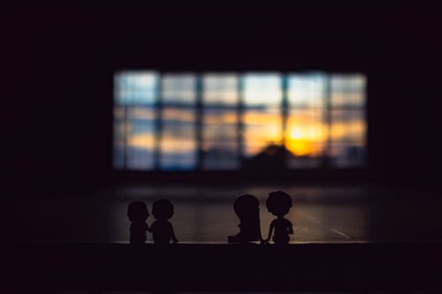 Free Silhouettes of cute figurines placed on surface against window with sunlight on blurred background in dark room in evening time Stock Photo