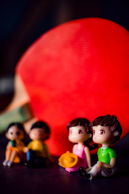 Free Cute colorful figurines of couples placed on surface near ping pong racket in light room on blurred background at home Stock Photo