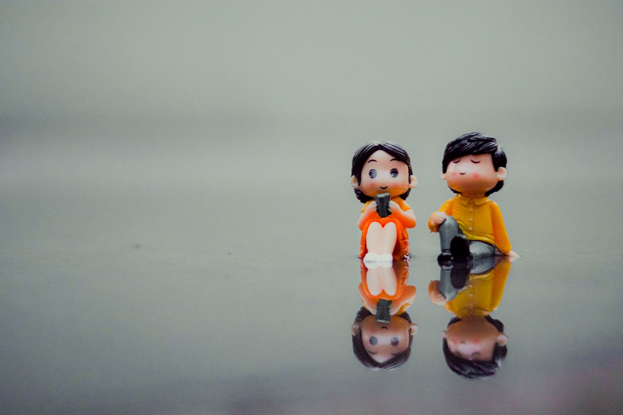 cute colorful miniatures of boy and girl with black hair reflecting on