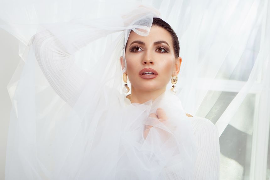 Model wearing statement gold earrings draped in tulle — Inna Mykytas on Pexels