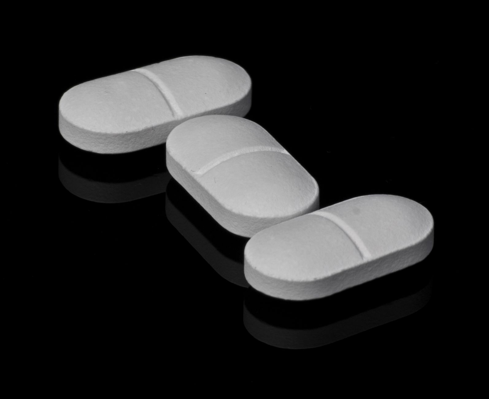 Ivermectin protocol guide — Three white tablets placed on a black reflective surface, highlighting pharmaceutical theme.