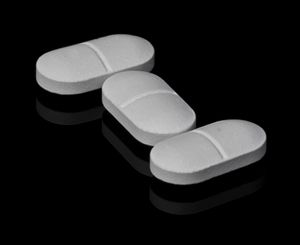 Three white tablets on a dark reflective surface — photo by David Peterson on Pexels