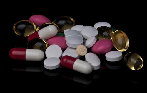 Assorted Pills and Tablets Piled on a Black Surface